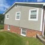 A grey house with a brick foundation.