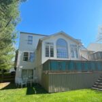 House with a large window and stairs leading to a deck.