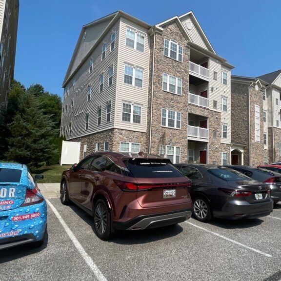 Many cars parked in front of an apartment complex building